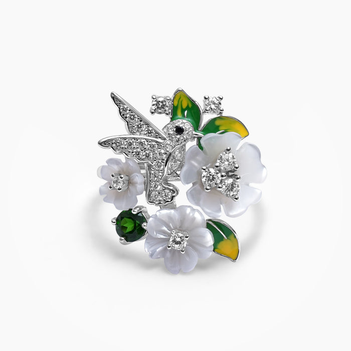 A sterling silver ring with a design of a bird and flowers, encrusted with zircons and mother of pearl, respectively.