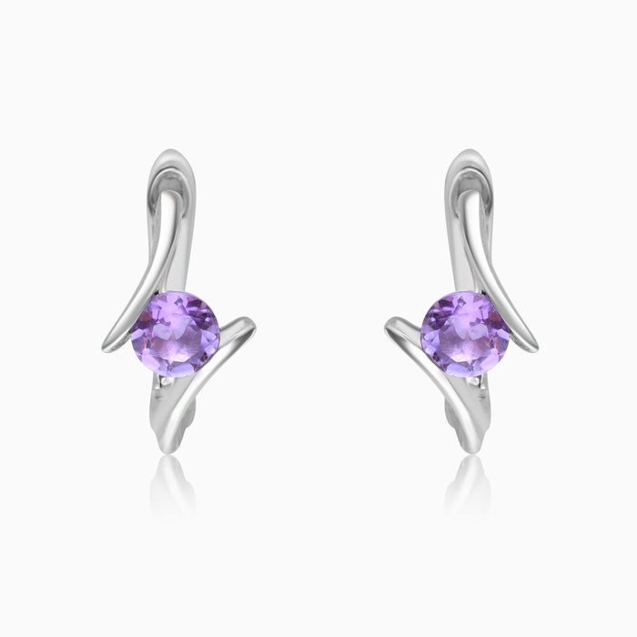 A pair of silver hoop earrings with amethyst stones set in them, displayed against a white background.