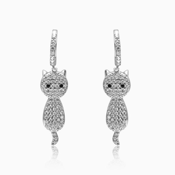 A pair of silver dangling hoop earrings with a cute cat design, adorned with small sparkling stones.
